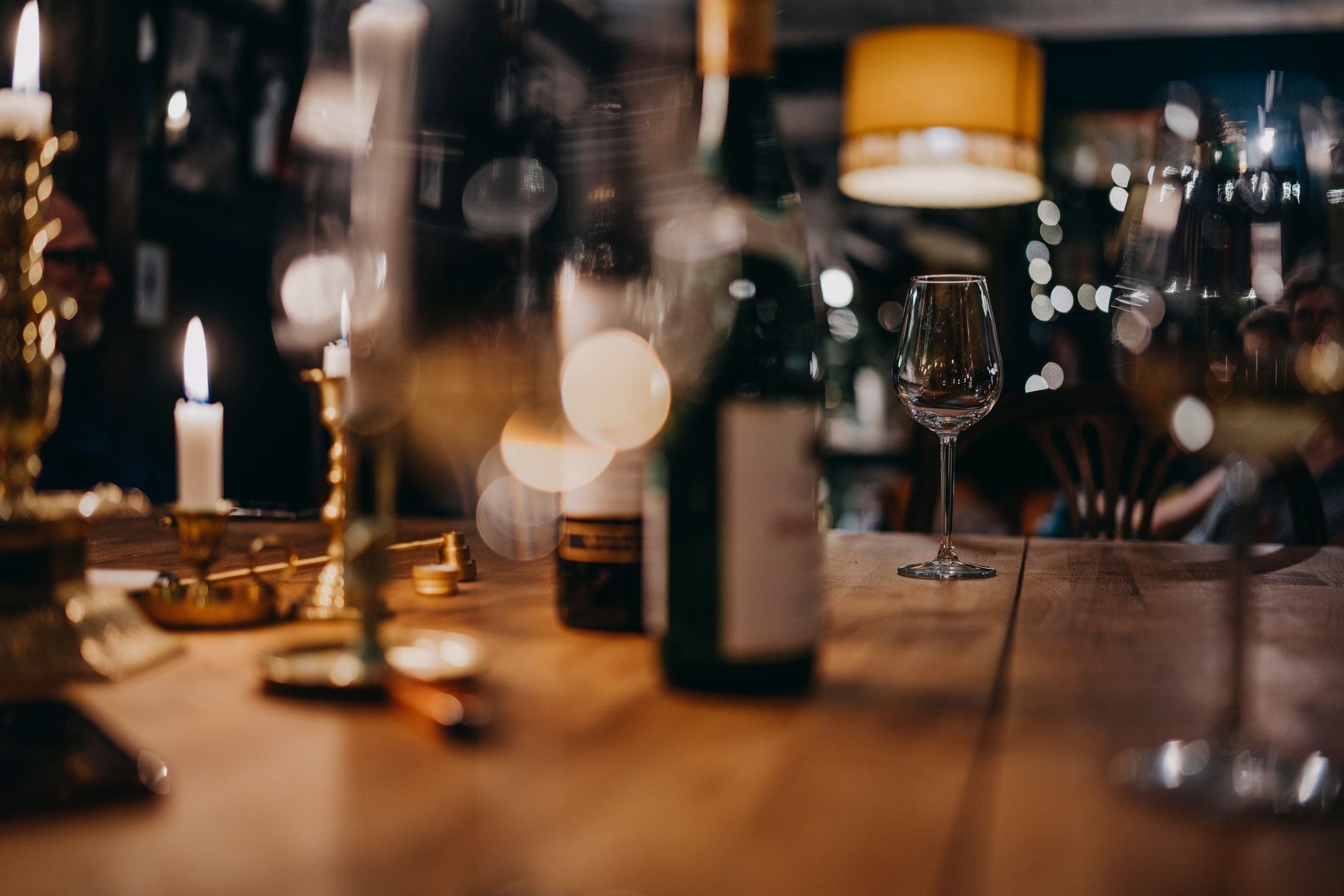 Mum ışığında ahşap masa: şişe, kadeh, pirinç şamdan